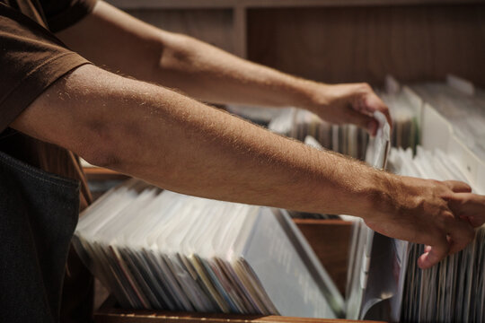 Vinyl crate digging and music discovery, hands browsing records in store through analog curation beyond streaming algorithms and automated recommendations