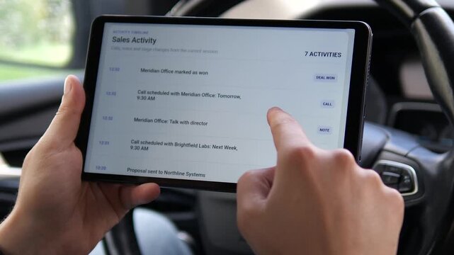 Sales professional reviews CRM activity on a tablet inside a car, tracking calls, proposals and won deals to manage a mobile sales pipeline and customer follow-up.