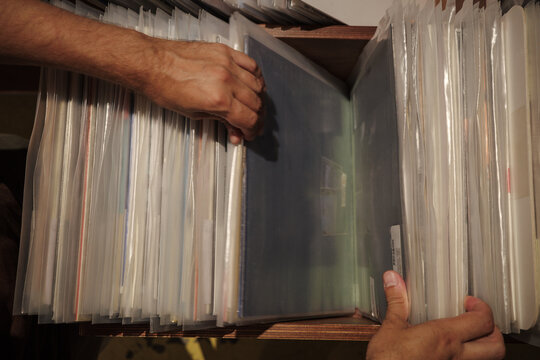 Slow vinyl shopping as mindful analog hobby, hands selecting records for intentional leisure, tactile ritual, relaxation and screen-free living