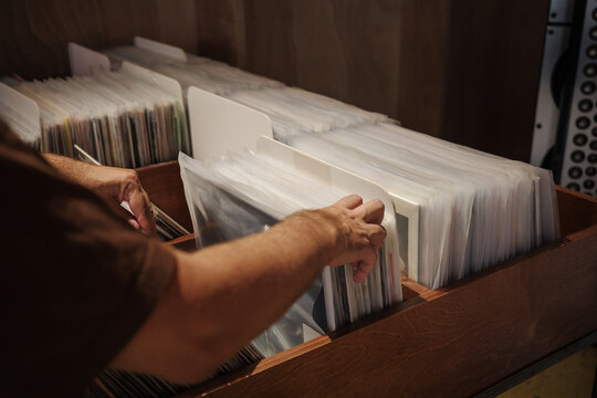 Physical vinyl ownership, man selecting records in music shop and choosing tangible media for offline listening, personal collection and independence from streaming subscriptions