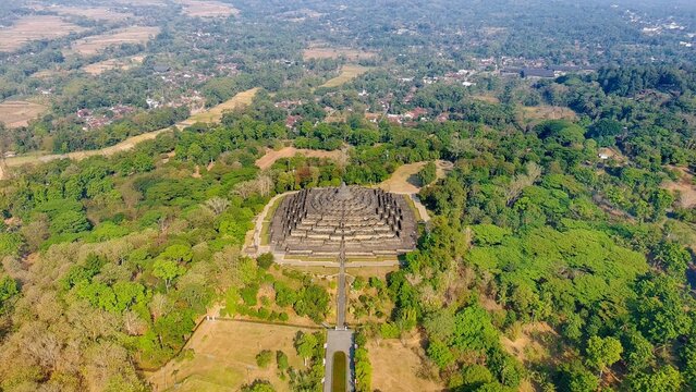 Aerial view of Borobudur Temple surrounded by lush green forest and trees in Kecamatan Borobudur, Jawa Tengah, Indonesia.