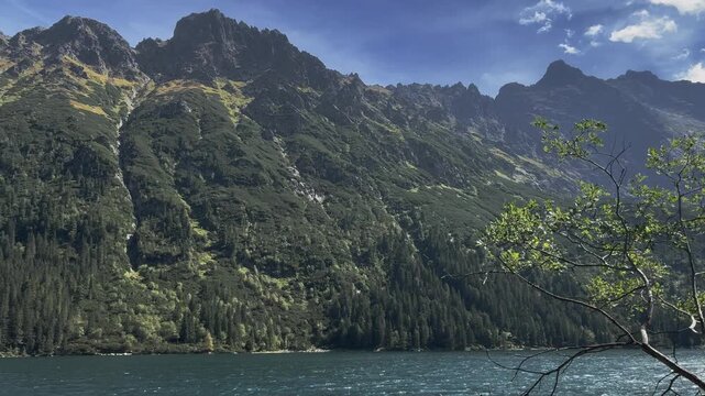 Panoramic view of Morskie Oko lake surrounded by majestic rocky peaks and green forests in Tatra Mountains, Poland, summer alpine landscape.