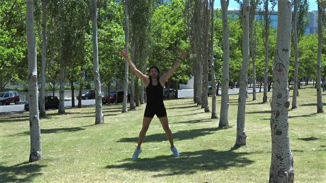Outdoor cardio training featuring a young man executing jumping jacks