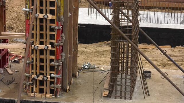 Construction site with yellow column formwork and brick wall, ready for concrete pouring. Column frame that has been installed and column formwork installed
