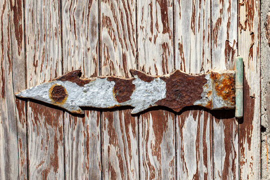 Rusty iron hinge weathered by sea air on an old wooden door