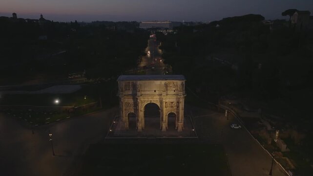Aerial view of the illuminated Arch of Constantine at night with surrounding city streets in Roma, Lazio, Italy.