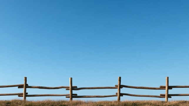 A long run of wooden fence stretches across the lower section of the frame, with vast blue sky filling the upper two thirds.