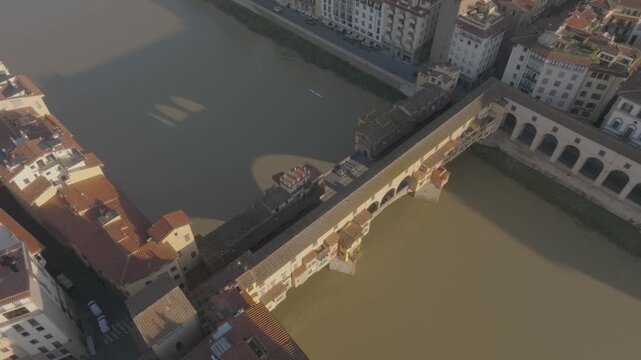 Aerial view of the historic Ponte Vecchio bridge spanning the Arno River with surrounding medieval architecture in Florence, Tuscany, Italy.
