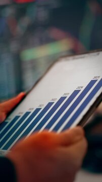 Digital Tablet Screen Upward Trend Bar Chart Analytics. Close up of a business person analyzing annual financial growth statistics and ascending bar graph on a tablet screen in a modern workplace