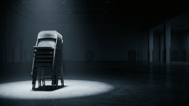 Spotlit stack of folding chairs in an empty convention hall, summit season and empty venue concept