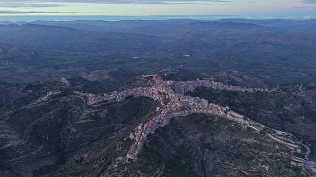 Aerial view of the star-shaped town of Centuripe set amidst the rolling hills of the Sicilian landscape at dusk in Centuripe, Sicily, Italy.