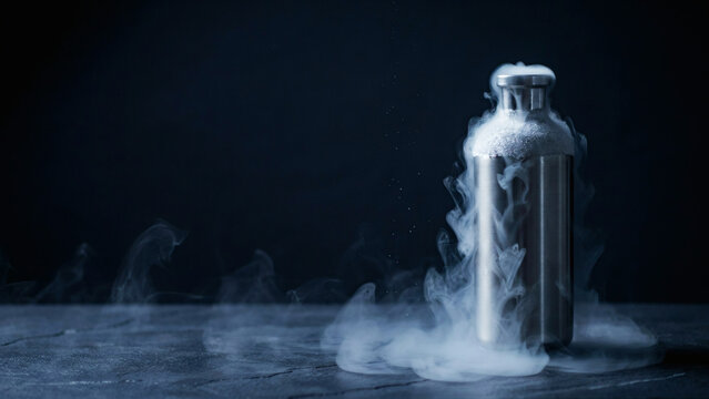 Frosted steel cryogenic gas container venting cold vapour on a dark surface for spot LNG cargo trading, concept