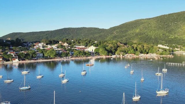 Fast motion aerial drone shot flying straight from the sea towards the historic Nossa Senhora das Necessidades church plaza in Santo Antonio de Lisboa, Florianopolis, Santa Catarina, Brazil.
