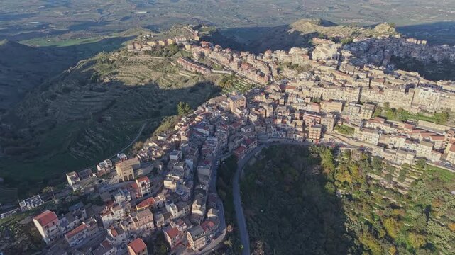 Aerial view of the historic hilltop town of Centuripe with its dense stone buildings and winding streets set against the rugged Sicilian landscape in Centuripe, Sicily, Italy.