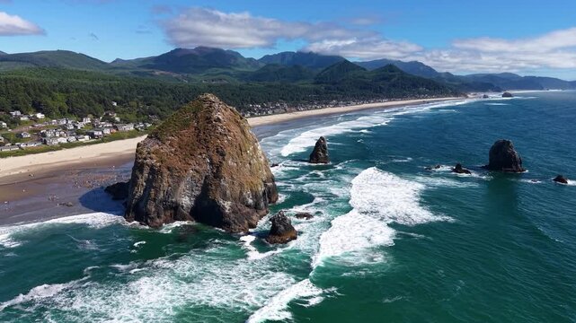OREGON - 9.2.2026 - Incredible aerial footage moving over rock formations off Oregon's Cannon Beach, towards scenic mountains.