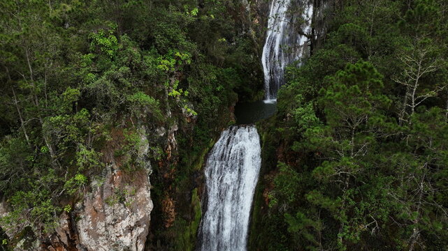 Aerial view of Salto de Aguas Blancas waterfall cascading down rocky cliffs surrounded by dense green forest in Constanza, La Vega Province, Dominican Republic.