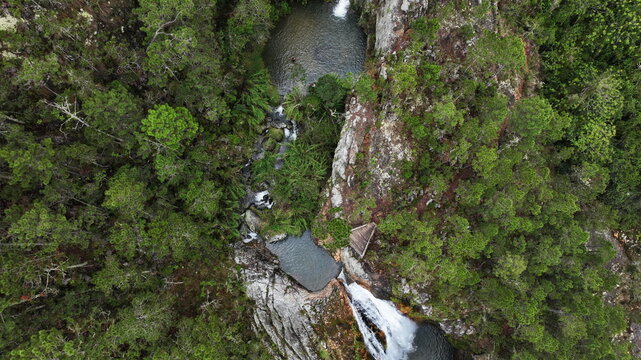 Aerial view of Salto de Aguas Blancas waterfall cascading through a lush green forest with rocky cliffs and natural pools in Constanza, La Vega Province, Dominican Republic.