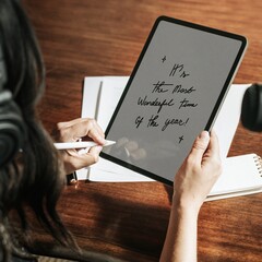 Designer drawing holiday greetings typography on tablet © Rawpixel.com