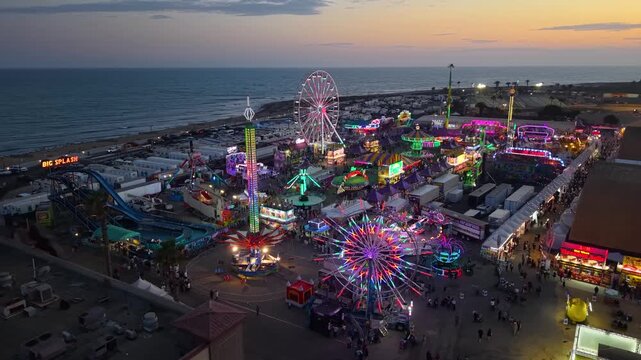 CALIFORNIA - 9.2.2026 - Excellent aerial footage circling the beachfront Ventura County Fair's carnival rides at sunset.