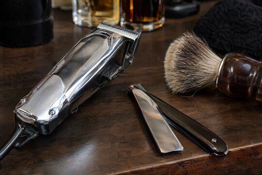 Barber clippers straight razor and shaving brush on wooden counter
