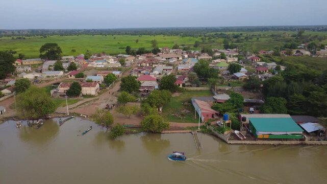 GAMBIA - 12.19.2025 - Very good aerial footage following a boat as it sails past a garden camp on the banks of the Gambia River.