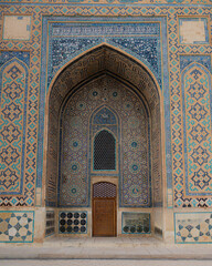 Ornate tiled archway with intricate blue geometric patterns and a recessed doorway, showcasing decorative architecture ideal for heritage, travel and cultural design themes. © UQink