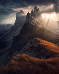 Sunbeams break through clouds above a dramatic mountain ridge, illuminating warm slopes and dark valleys in an epic landscape ideal for travel, adventure, hiking and inspirational nature themes. © UQink
