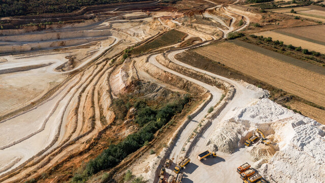 Aerial view of the Besenovo quarry showing terraced limestone extraction levels, heavy machinery, and trucks working on the site in Besenovo, Vojvodina, Serbia.