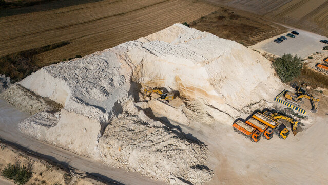 Aerial view of the Besenovo quarry with excavators and dump trucks working on large piles of white limestone in Besenovo, Vojvodina, Serbia.