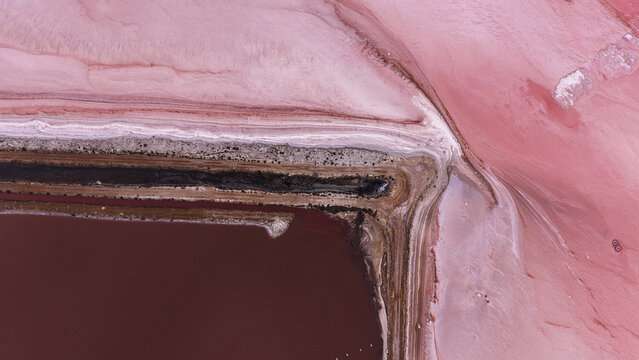 Aerial view of vibrant pink salt production ponds with textured embankments and mineral-rich water in Kalbarri, Western Australia, Australia.