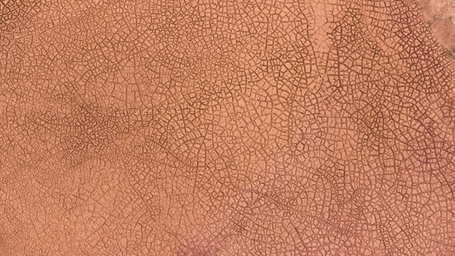 Aerial view of the intricate cracked patterns of a salt pan with textured reddish-orange earth in Kalbarri, Western Australia, Australia.