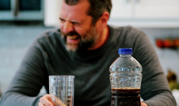 Middle aged man drinking prune juice to aide digestive health naturally - gut health constipation relief remedy aging gracefully preventive wellness