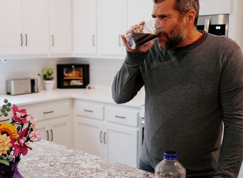 Middle aged man drinking prune juice to aide digestive health naturally - gut health constipation relief remedy aging gracefully preventive wellness