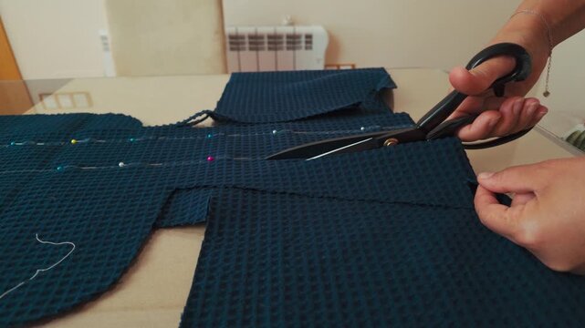 Hands Cutting Blue Textured Fabric for a Sewing Project with Large Tailor Scissors