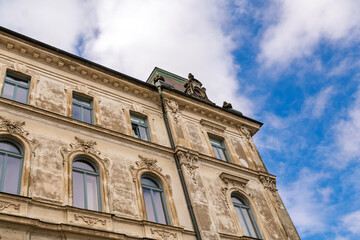 Low angle view of historic baroque building facade with ornate stucco details against blue sky and clouds, European architecture © Yuliko