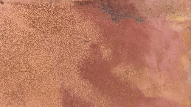 Aerial view of the cracked, textured surface of salt flats near Useless Loop, showcasing intricate industrial patterns and earthy tones in Kalbarri, Western Australia, Australia.