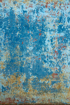 A vertical abstract texture background featuring a sheet of metal coated in bright blue paint. The paint layers are heavily chipped, scraped, and scratched away, revealing a dense base of brown and or