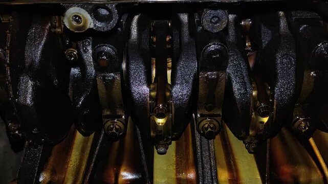 Under-car view of an open engine crankcase showing the oily crankshaft, counterweights, connecting rod caps, and internal mechanical components.