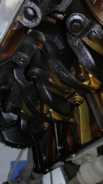 Under-car view of an open engine crankcase showing the oily crankshaft, counterweights, connecting rod caps, and internal mechanical components.