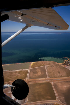 Aerial view of the salt pans and industrial patterns at Useless Loop with brown and yellow sand deposits near the coastline in Kalbarri, Western Australia, Australia.
