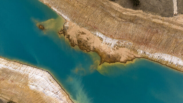 Aerial view of turquoise salt mine waters contrasting with textured sandy banks and industrial earth patterns, Kalbarri, Western Australia, Australia.