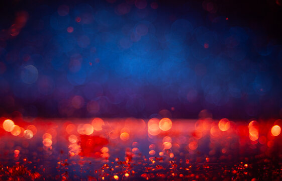 Colorful lights reflect on a wet surface during evening hours in a city setting