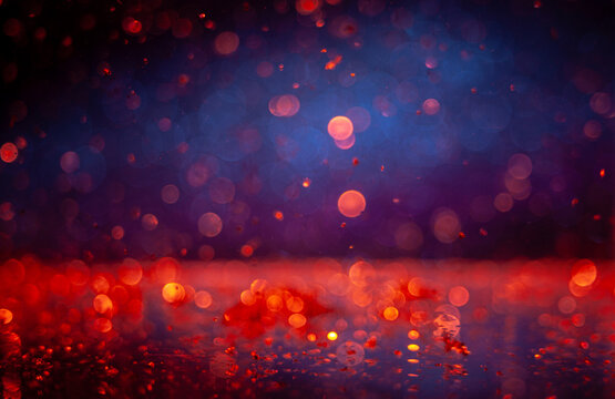 Colorful lights reflect on a wet surface during evening hours in a city setting