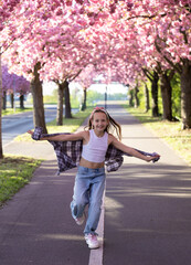 Obraz premium Playful girl running with shirt under blooming cherry blossom trees in spring park