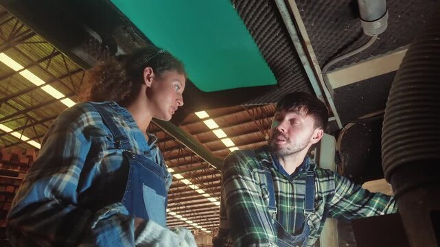 Two people work on machinery in a workshop, demonstrating their skills and focus on a project