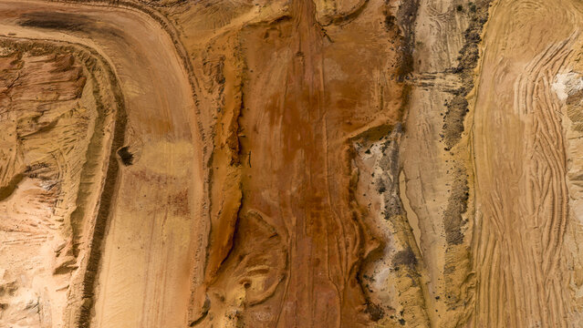 Aerial view of industrial salt mining patterns at Useless Loop, showing textured sand and earth in shades of brown and yellow after a storm in Kalbarri, Western Australia, Australia.