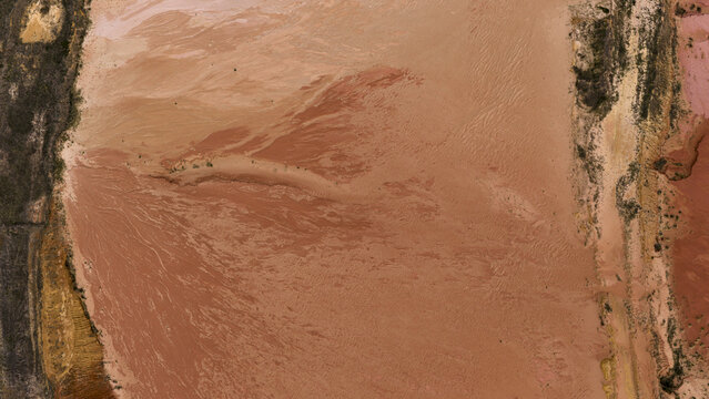 Aerial view of salt lake industrial patterns near Useless Loop, featuring brown and yellow sand deposits and salt formations in Kalbarri, Western Australia, Australia.