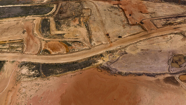 Aerial view of industrial patterns and sand deposits at Useless Loop salt mine, showing brown and yellow earth after a storm in Kalbarri, Western Australia, Australia.