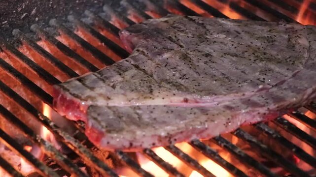 Carne gruesa as&aacute;ndose a la parrilla mientras se voltea sobre el fuego