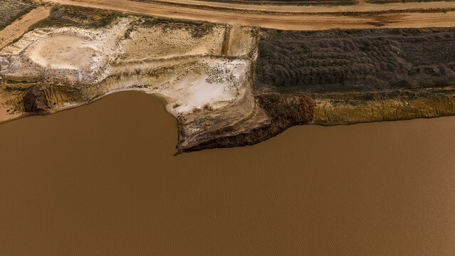 Aerial view of industrial salt mining patterns with brown water, sand deposits, and textured earth near Useless Loop in Kalbarri, Western Australia, Australia.